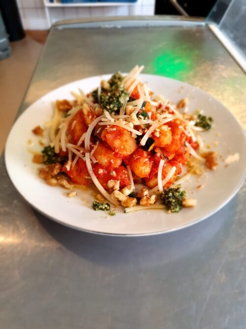 Gebakken gnocchi met tomatensaus, courgette, pesto, parmezaan en walnoten