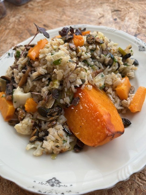 Gevulde pompoen met rijst, nootjes, champignon, groenten, romige tahin dressing en geroosterde pompoenpitten