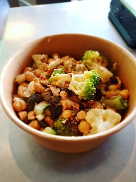 Salade met geroosterde bloemkool en kikkererwten, met groene kruiden, tahindressing en granaatappel