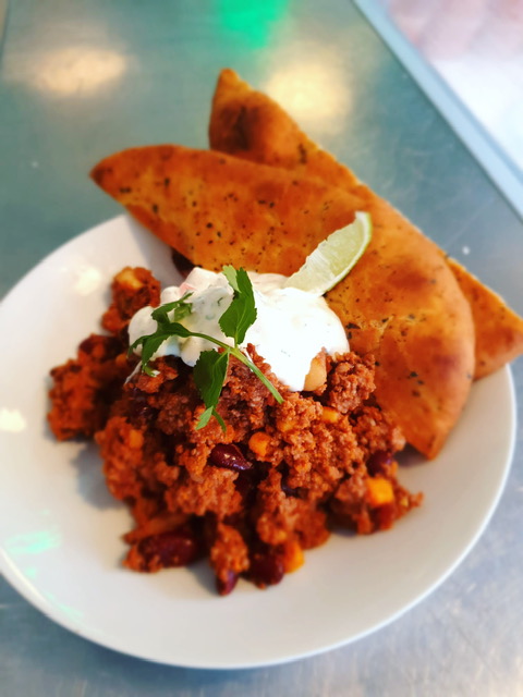 Chili con carne met een knoflookbroodje en creme fraiche