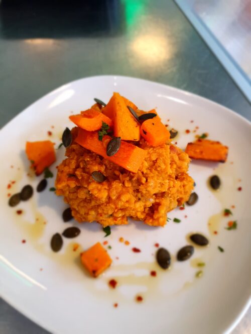 Romige dahl van rode linzen en tomaat. Met geroosterde pompoen en pompoenpitten