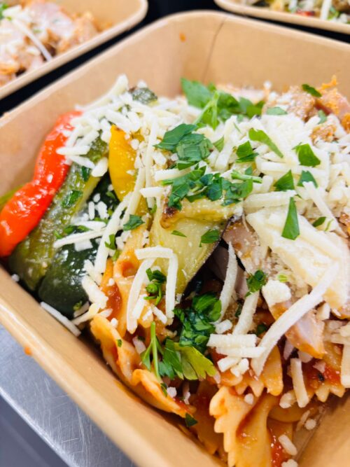 Farfalle met tomatensaus, geroosterde groenten en gegrilde kipdij. Met Parmezaan