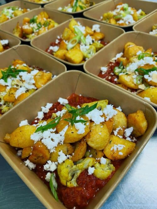 Knapperige aardappeltjes met in ras el hanout gemarineerde bloemkool, een volle tomatensaus, feta en amandel
