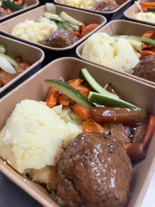 Een dikke slagers gehaktbal met gegrilde groenten, aardappelpuree en jus